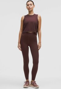 Burgundi spalvos sportinis topas ir aukštos juosmens legging'ai, abu pagaminti iš tamprios medžiagos. Кartu su šviesiai rožiniais sportiniais bateliais.