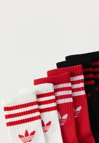 Ponožky do stredu lýtka v bielej, červenej a čiernej farbe. Rebrovaná textúra s tromi horizontálnymi pruhmi. Každý pár má na členku logo s kvetinovým motívom.