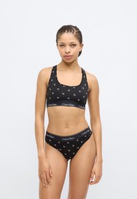 Μαύρο βαμβακερό αθλητικό σουτιέν και ταιριαστό μπικίνι με λευκό μοτίβο λογότυπου CK, με τετράγωνη λαιμόκοψη και ελαστική μέση.