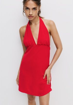 Robe rouge à encolure halter, en tissu texturé, avec un décolleté en V profond et un corsage ajusté, présentant une jupe légèrement évasée.