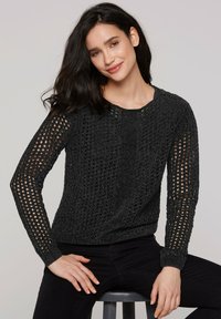 Schwarzer Strickpullover mit einem lockeren, offenen Design und langen Ärmeln. Verfügt über einen runden Halsausschnitt und gerippte Bündchen.