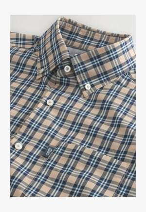 Kockás ing, bézs, sötétkék és világoskék színben, gombos pikkelyezéssel. Klasszikus gallérral és fehér műanyag gombokkal ellátva. Texturált, szőtt anyag.