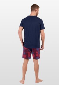 Marinblå bomullströja kombinerad med vinröda shorts med ett blommönster i röd och blå. Designen har rund hals och korta ärmar.