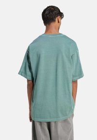 Mentolově zelené oversized tričko vyrobené z měkké bavlněné látky, s kulatým výstřihem a krátkými rukávy, s jednoduchým, bezšvovým designem.