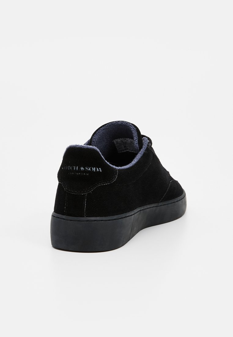 Zapatillas de ante negro con un acabado texturizado, perfil bajo, puntera redonda y forro interior azul en contraste. Presenta suela de goma negra plana y tab de soporte en la parte posterior.