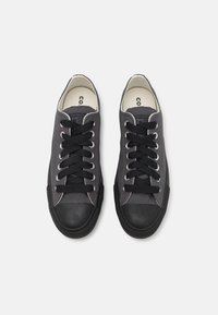 Szare płócienne sneakersy z czarnym gumowym dnem i sznurowadłami, charakteryzujące się minimalistycznym designem i teksturowanym materiałem.