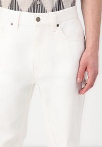 Witte denim jeans met een rechte pasvorm, vijf-pocket ontwerp, contrasterende stiksels en metalen knoophardware bij de taille.