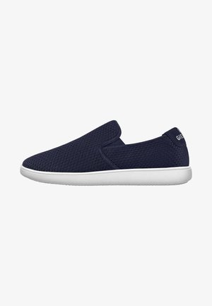 Chaussures à enfiler bleu marine avec une tige en maille texturée, semelle en caoutchouc blanc et un branding minimal au niveau du talon pour un design simple.