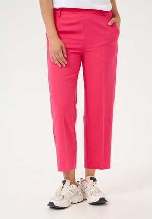 Pink tailored trousers feature a slim fit with a slightly cropped length, side pockets, and a smooth, lightweight fabric texture.