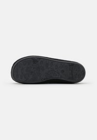 Black shoe sole with textured rubber, featuring oval grips for traction, and smooth edges. Material appears durable and flexible.