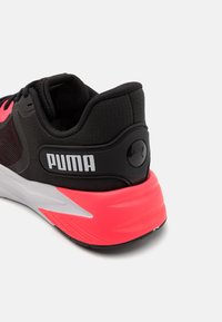 Black athletic shoe with pink accents, featuring a textured mesh upper, padded collar, and large "PUMA" logo on the heel.
