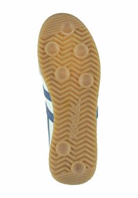 Semelle de chaussure en caoutchouc beige avec un motif en zigzag et des crampons circulaires. Présente des accents bleus sur un fond blanc.