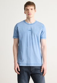 T-shirt de algodão azul claro com decote redondo e mangas curtas; apresenta um discreto logo "BOSS" azul escuro no peito. Design simples, textura suave.