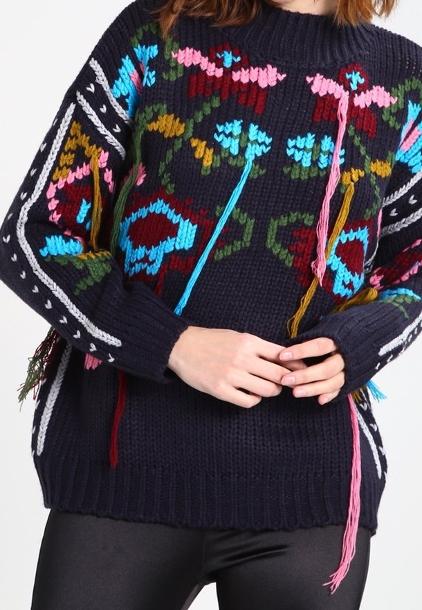 Námořnicky modrý pletený svetr s výraznými květinovými vzory v růžové, modré a zelené. Obsahuje třásně na rukávech a lemu.