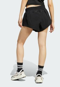 Svarta sportshorts med elastisk midja, med en stilren design och lös passform. Matchas med vita sneakers och randiga strumpor.