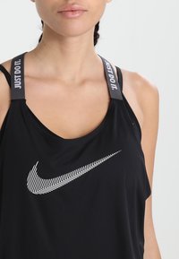 Canotta sportiva nera con scollatura rotonda, con il logo Nike bianco e il testo "Just Do It" sulle spalline. Texture liscia.