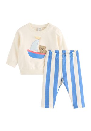 Kremfarvet babybluse med lange ærmer, dekoreret med applikation af en sejlbåd og en tøjbamse, kombineret med bukser i blå og hvide lodrette striber.
