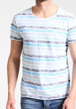 Mann trägt ein kurzärmliges T-Shirt mit Rundhalsausschnitt und horizontalen Streifen in Blau-, Weiß- und Schwarztönen, kombiniert mit blauen Jeans.