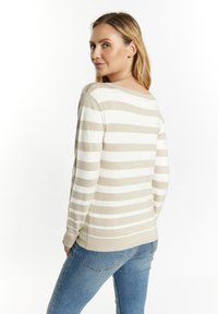 Beiger und weiß gestreifter Pullover mit rundem Ausschnitt und langen Ärmeln, kombiniert mit hellblauen Jeans. Weiche Textur und lässige Passform.