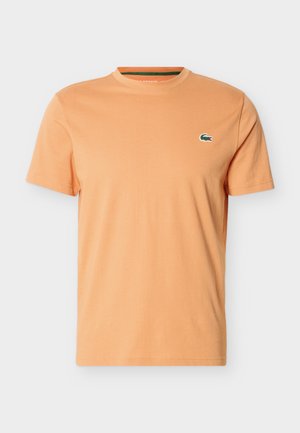 Men's plain light orange short-sleeve crew neck t-shirt with small green crocodile logo on left chest.