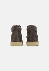 Botas de tobillo de ante gris oscuro con puntera redonda, detalles de costura y suela de goma clara. Presenta un acolchado suave en el collar y un diseño minimalista.