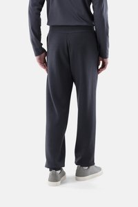 Dunkelgraue Jogginghose mit entspanntem Schnitt, geripptem Bund und seitlichen Taschen, kombiniert mit grauen Sportschuhen vor einfarbigem Hintergrund.