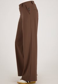 Bruine broek met wijde pijpen, voorzien van een gladde textuur, een platte voorkant met zijzakken, gestikte naden en een detail van een waistbandlabel.