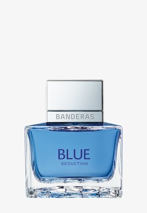 Bouteille carrée en verre transparent contenant un liquide bleu, bouchon argenté gravé de "Banderas,", étiquetée "Blue Seduction" à l’avant.