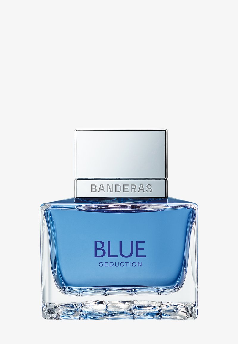 Firkantet klar glasflaske med blå væske, sølv låg med indgraveret "Banderas," mærket "Blue Seduction" på forsiden.