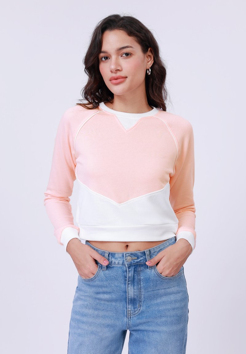 Felpa con un design a blocchi di colore rosa e bianco, caratterizzata da una cucitura a forma di V e polsini a coste, realizzata in tessuto morbido.