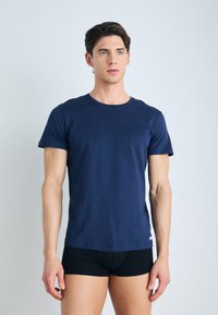 Camiseta de algodón azul marino con cuello redondo y manga corta, que presenta un corte ajustado y un diseño minimalista.