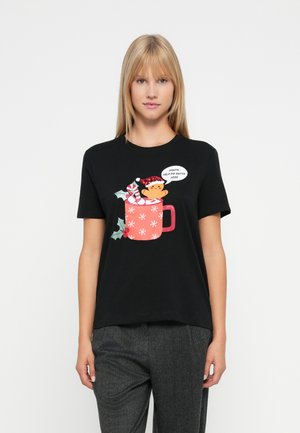 Sieviete, tērpusies melnā t-kreklā ar Ziemassvētku krūzes grafiku, tur piparkūku cilvēciņu un saka: "Ziemassvētku vecīt, palīdzi man tikt ārā."