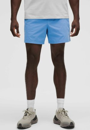 Ljusblå badshorts med en slät yta, i rakt snitt. Kombineras med neutrala sneakers och vita ankelsockar.