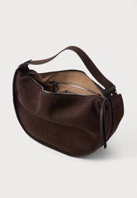 Brązowa zamszowa torba na ramię o gładkiej powierzchni, zakrzywionym kształcie, zamknięciu na zamek i skórzanym pasku. Wnętrze wykończone jest jaśniejszym materiałem.