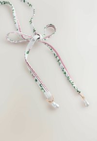 Virágos szövetből készült nyaklánc rózsaszín és zöld mintával, masnira kötve; mindkét végén csepp alakú fehér gyönggyel díszített medál található.