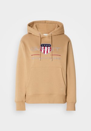 Sudadera con capucha en color marrón claro, que presenta un bolsillo frontal, puños acanalados y un logo con acentos en rojo y azul. Material suave de mezcla de algodón.