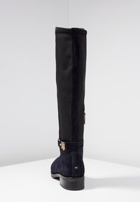 Stivale da donna in suede e tessuto nero, alto, con tacco basso, zip laterale, cinturino con fibbia dorata e piccolo logo sul tallone.