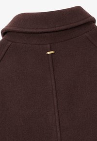 Brown wool coat with a notched collar, featuring a gold metal logo detail near the neck and a textured finish.