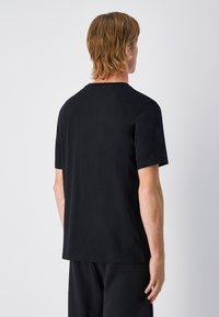 Camiseta negra de tela suave, con mangas cortas, cuello redondo y un diseño liso sin patrones ni acentos.