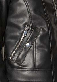 Zwarte leren jas met een zijritszak met zilveren hardware, een gladde textuur en opvallende stikdetails op de stof.