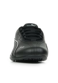 Chaussure de sport noire avec une tige en cuir lisse, des détails de couture texturée et une semelle en caoutchouc noire. Elle dispose de lacets et d'un logo de marque.