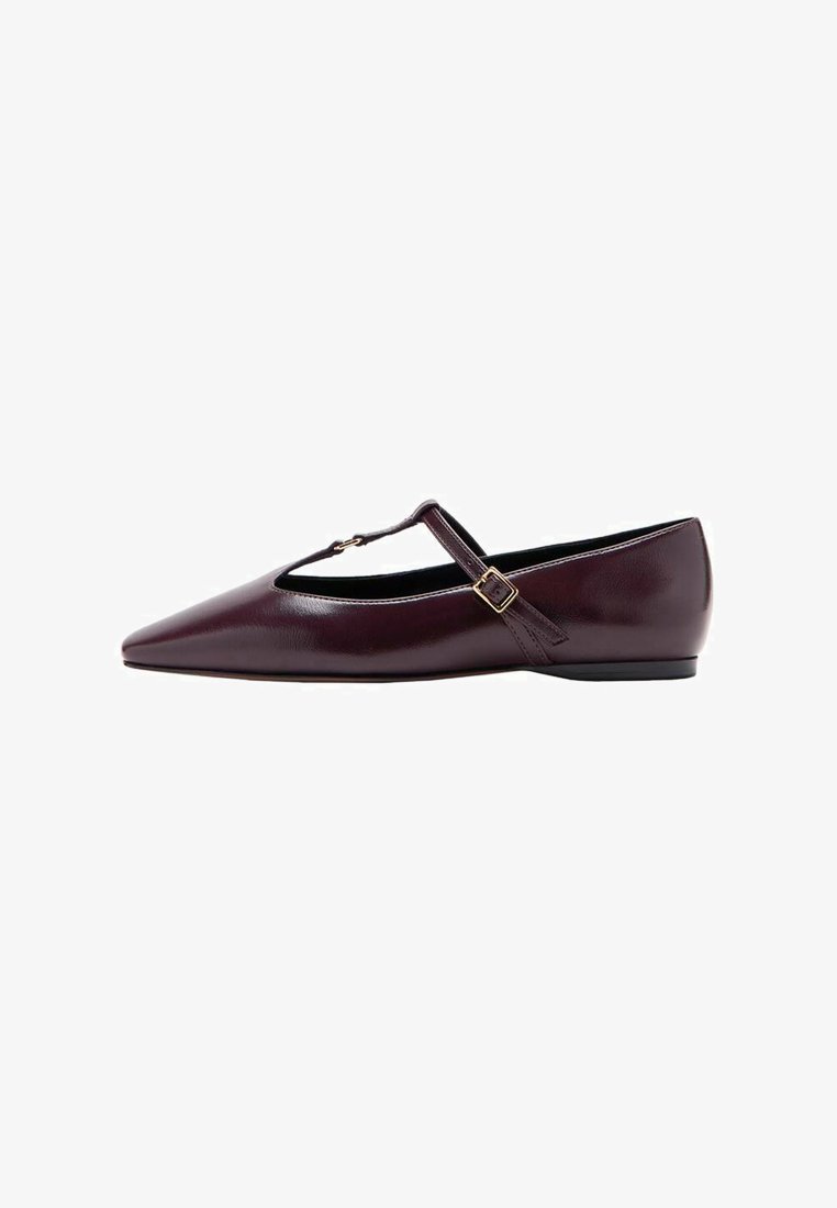 Zapato plano de punta afilada en cuero burdeos oscuro. Cuenta con una correa en forma de T con una hebilla pequeña y un tacón bajo. Textura suave con acentos mínimos.