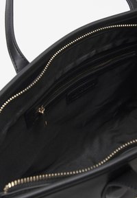 Borsa a mano in pelle nera con texture liscia, doppi manici superiori, scomparti con zip e dettagli in metallo dorato. L'interno presenta una fodera in tessuto.