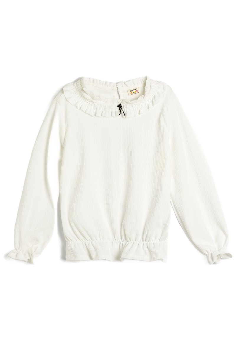 Maglietta bianca a maniche lunghe con colletto arricciato, vita arricciata e abbottonatura sul retro. Tessuto morbido e textured con polsini elasticizzati.