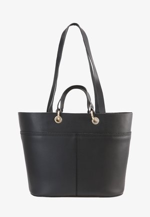 Sac cabas en cuir noir avec doubles poignées courtes et longue bandoulière, anneaux métalliques dorés attachant les poignées au sac.