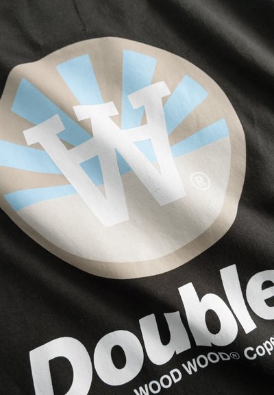 Un tessuto nero con grandi elementi di design: un logo circolare in beige e azzurro chiaro con le iniziali "W" e il testo "Double" sotto in bianco.