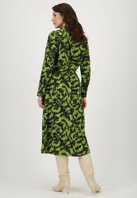 Groene en zwarte jurk met een patroon, lange mouwen en een getailleerde taille, gemaakt van een lichtgewicht materiaal. Middellange uitvoering met een gladde textuur.