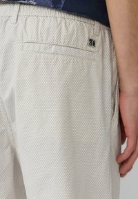 Helle beige Shorts aus Netzstoff mit Diamantmuster, elastischem Bund und einer Gesäßtasche mit einem kleinen Logostick.