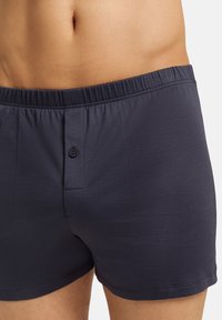 Námořnické modré bavlněné boxerky s elastickým páskem, jedním knoflíkem a hladkým povrchem. Standardní střih bez vzorů.