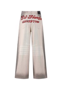 Pantalones de mezclilla beige de pierna ancha, con un logo bordado en rojo "Ed Hardy 1971" en la parte trasera y sutiles detalles de desvanecimiento horizontal.